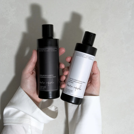 Meera Capsule Shampoo + Conditioner Bundle close-up — amber glass bottles with minimalist labels on neutral background