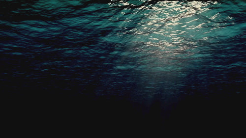 Underwater waves with light rays shining through the surface.